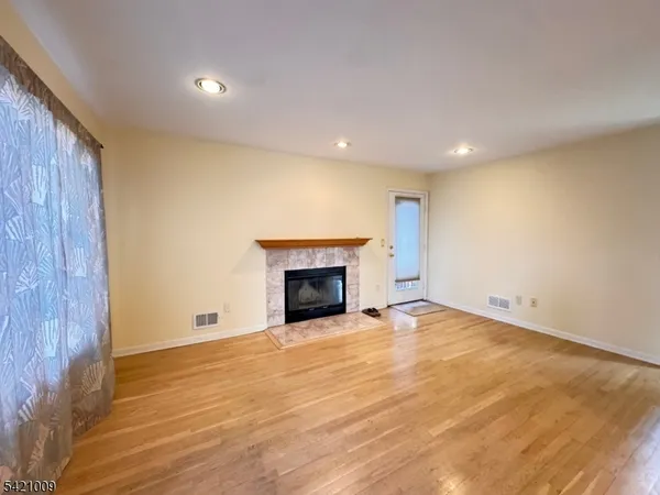an empty room with wooden floor fireplace and windows