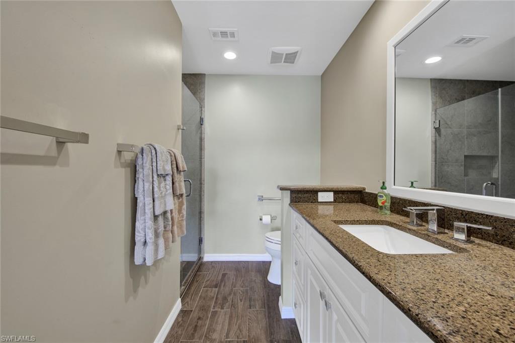 2912 West Crown Pointe Boulevard, Unit 141 Naples, FL 34112 - Photo 23 of 32 a bathroom with a granite countertop sink a mirror and a toilet