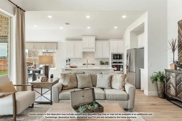 a living room with stainless steel appliances kitchen island granite countertop a refrigerator a sink a stove and white cabinets with wooden floor