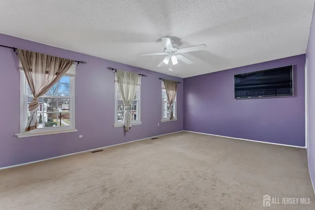 an empty room with windows and fan