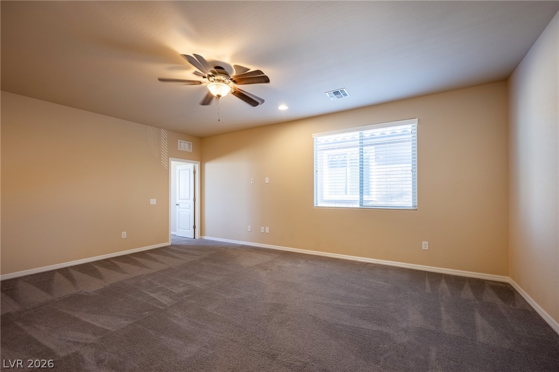 11016 Prairie Grove Road Las Vegas, NV 89179 - Photo 19 of 37 A spacious, naturally illuminated room featuring plush carpeting and a modern ceiling fan.