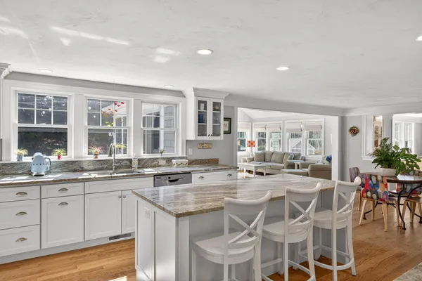 a kitchen with granite countertop lots of white cabinets stainless steel appliances and dining table