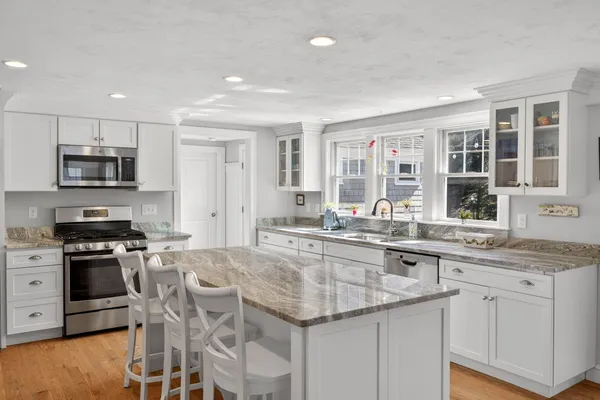 a kitchen with stainless steel appliances granite countertop a stove top oven a sink a dining table and chairs