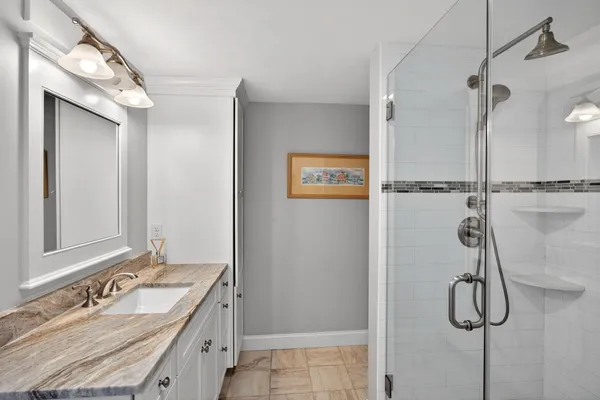 a bathroom with a granite countertop shower sink and mirror