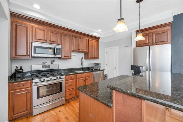 a kitchen with granite countertop stainless steel appliances a stove sink and microwave