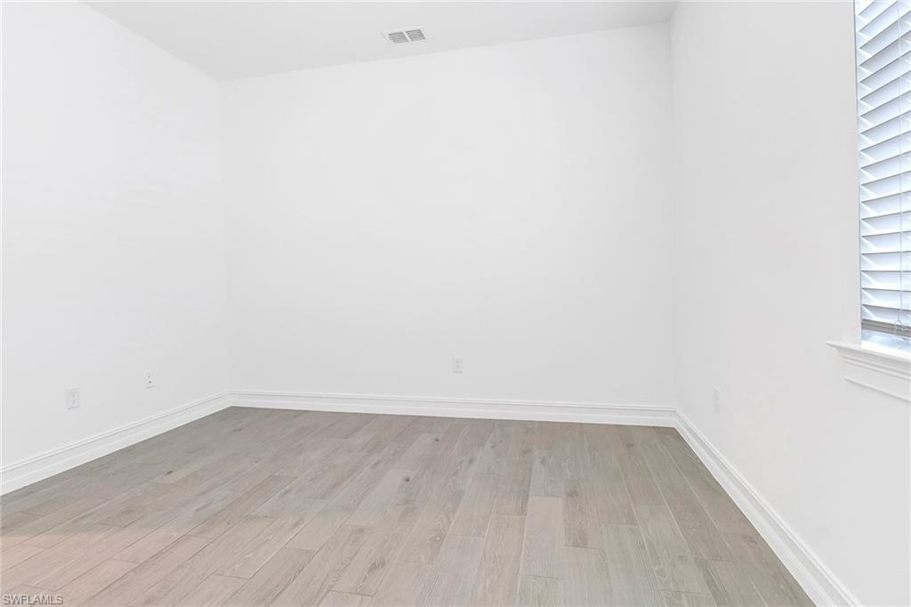 317 Spiaggio Court Naples, FL 34114 - Photo 13 of 46 a view of an empty room with wooden floor and a window