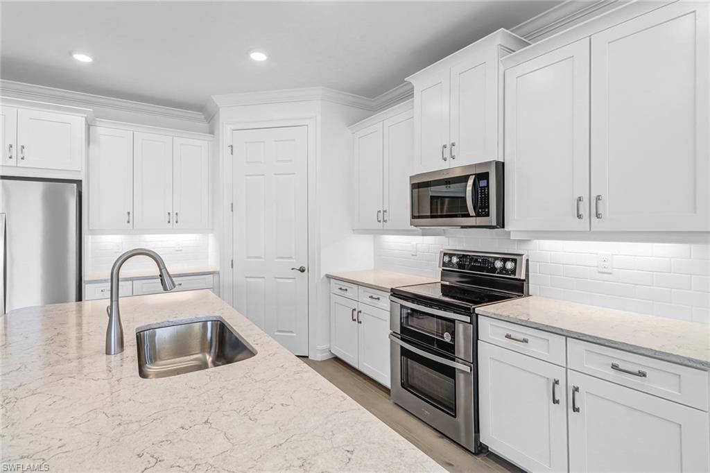 317 Spiaggio Court Naples, FL 34114 - Photo 19 of 46 a kitchen with white cabinets and stainless steel appliances