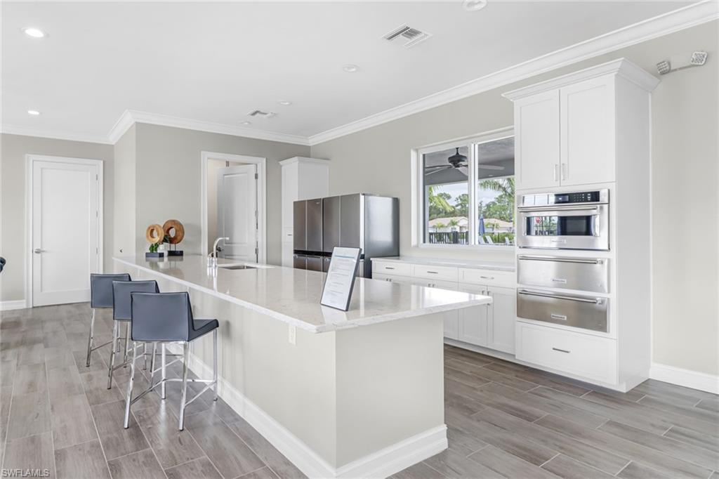 317 Spiaggio Court Naples, FL 34114 - Photo 42 of 46 a very nice looking living room with kitchen island furniture a large window and wooden floor