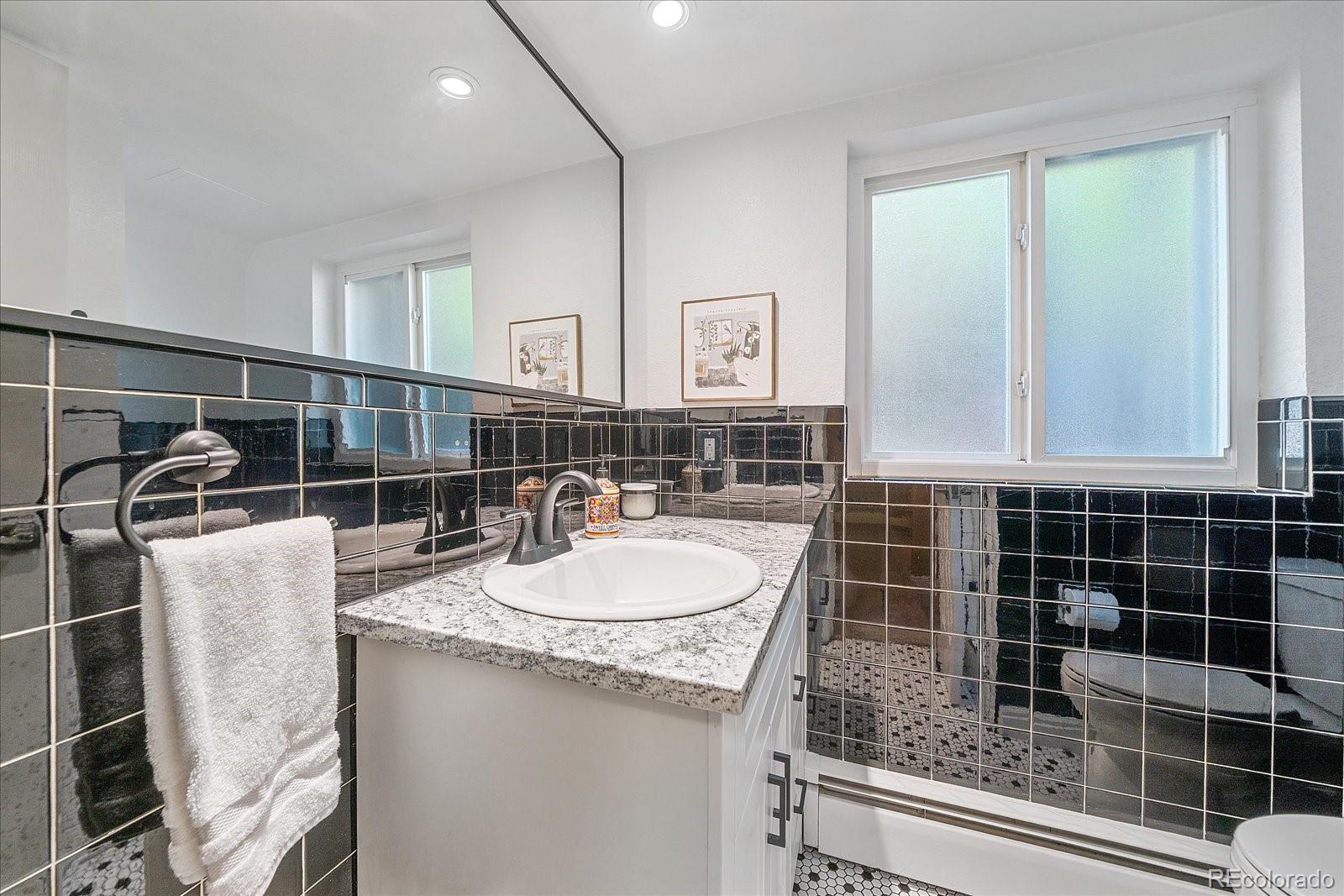 930 Reed Court Lakewood, CO 80214 - Photo 24 of 41 a bathroom with a granite countertop sink a mirror and a shower