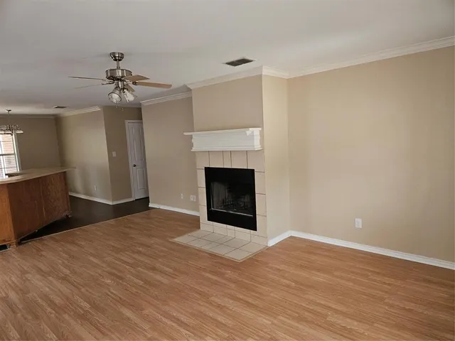 a view of an empty room with wooden floor and a fireplace