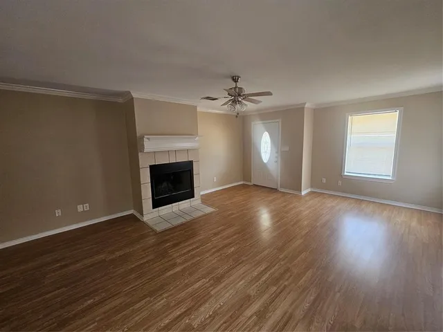 an empty room with wooden floor fireplace and windows