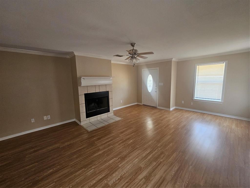 1605 Stuart Road Denton, TX 76209 - Photo 5 of 22 an empty room with wooden floor fireplace and windows
