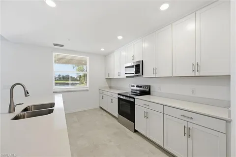 a kitchen with white cabinets and stainless steel appliances