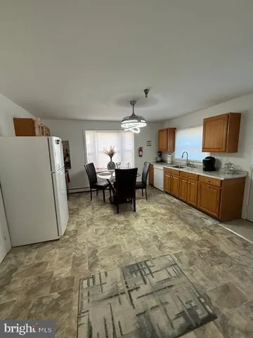 a large white kitchen with a stove a refrigerator and a dining table
