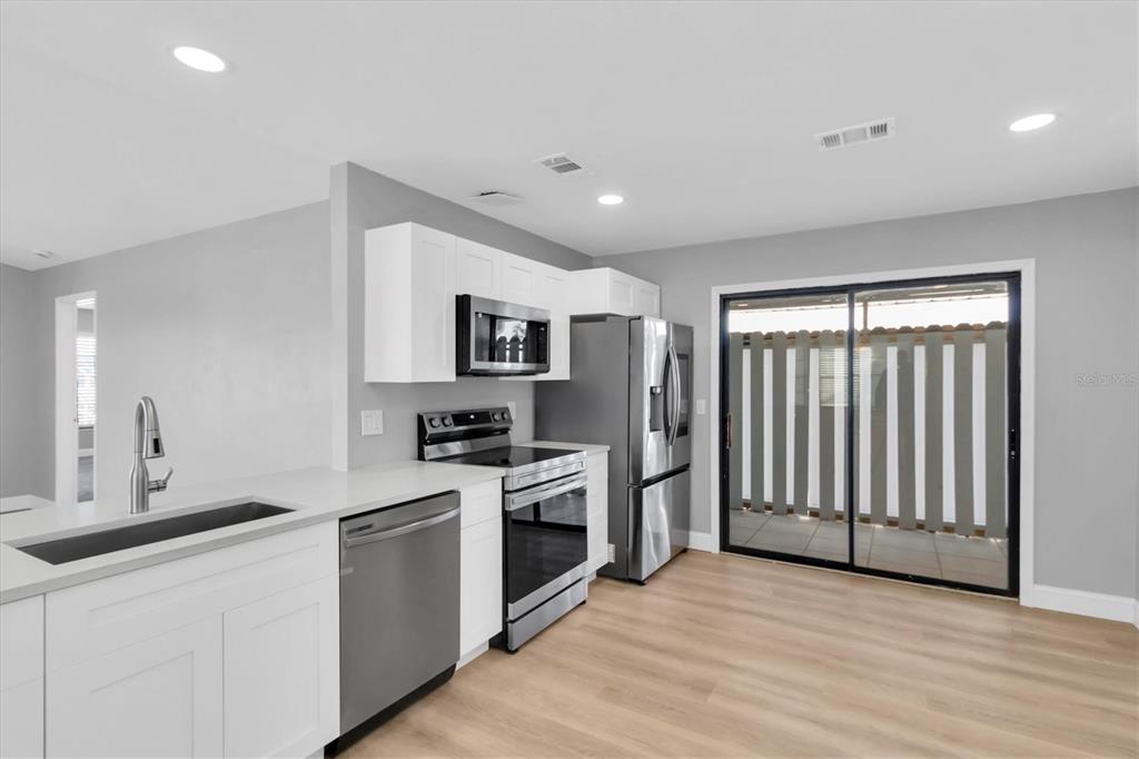 5925 Seaside Drive New Port Richey, FL 34652 - Photo 11 of 55 a kitchen with stainless steel appliances granite countertop a stove top oven a sink and a refrigerator