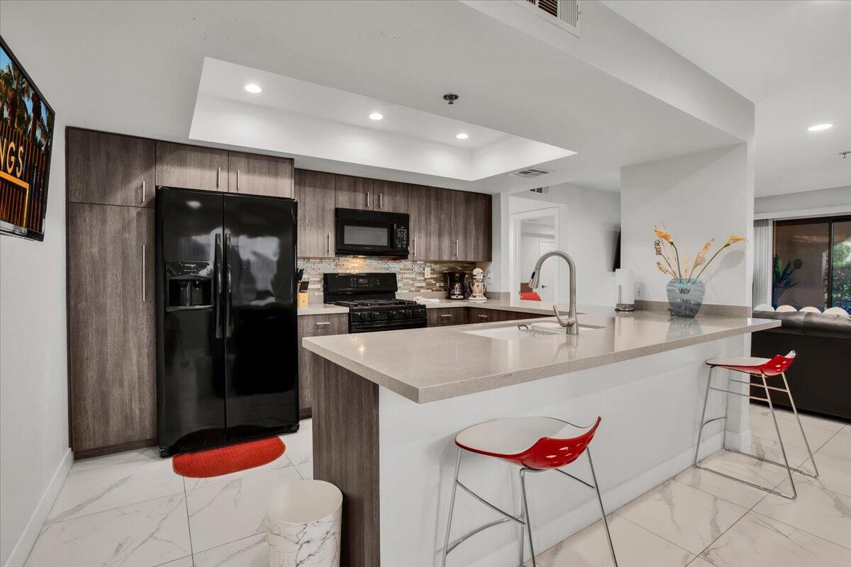 200 East Racquet Club Road, Unit 31 Palm Springs, CA 92262 - Photo 13 of 49 a kitchen with stainless steel appliances kitchen island granite countertop a sink refrigerator and microwave