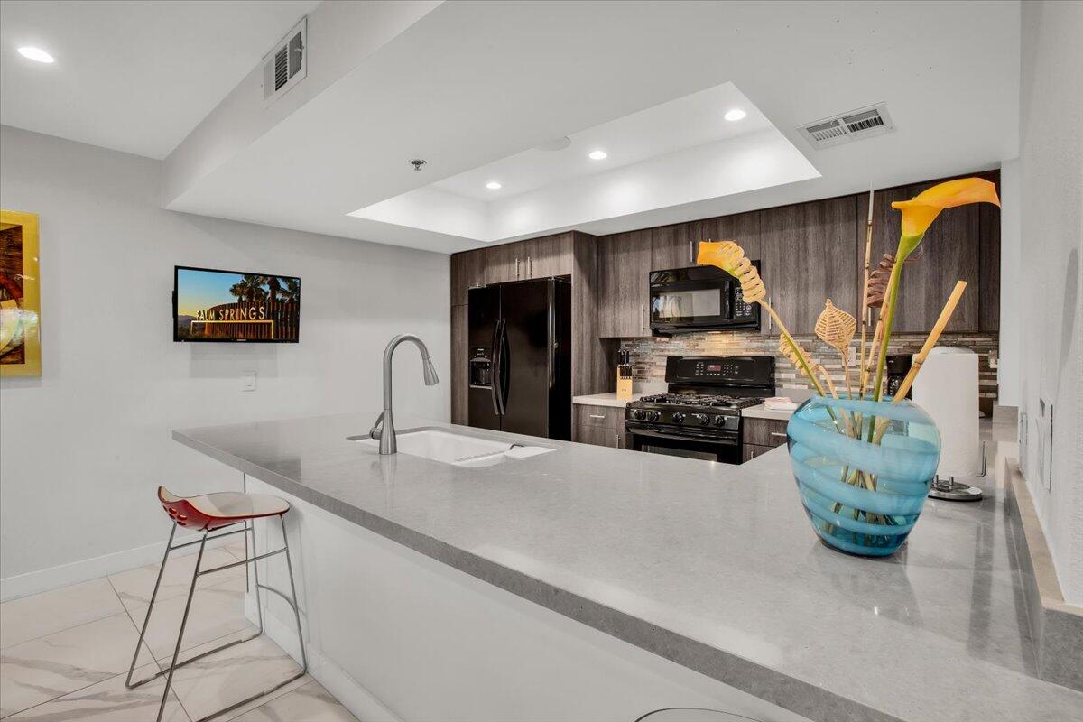 200 East Racquet Club Road, Unit 31 Palm Springs, CA 92262 - Photo 15 of 49 a kitchen with stainless steel appliances granite countertop a sink and a refrigerator