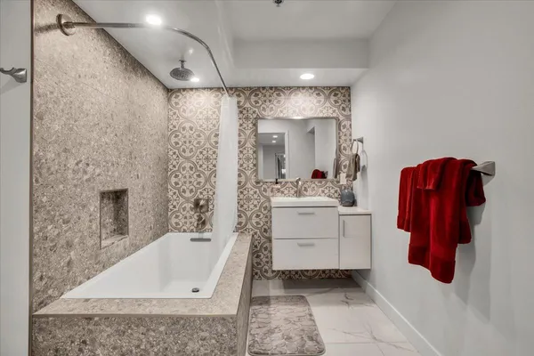 a bathroom with a tub sink and mirror