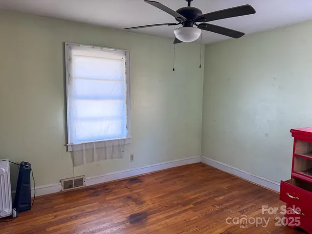 an empty room with wooden floor closet and windows