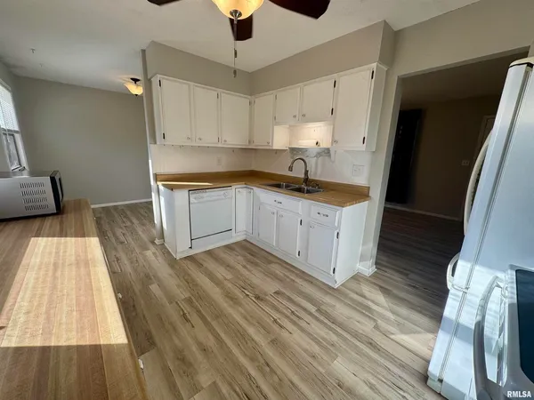 an empty room with wooden floor chandelier fan and windows