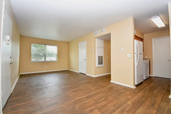 an empty room with wooden floor mirror and windows