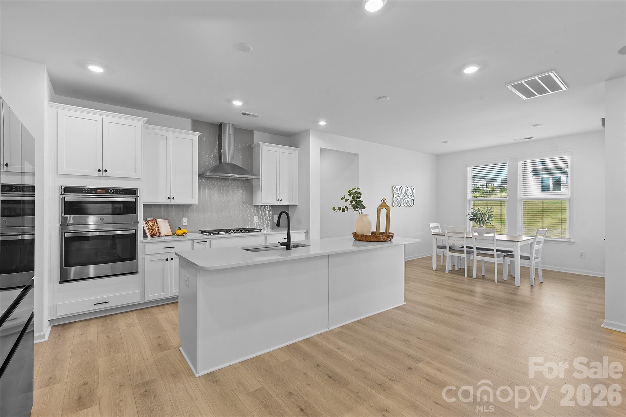 1170 Sugar Crk Road Fort Mill, SC 29707 - Photo 20 of 47 a large white kitchen with stainless steel appliances granite countertop a stove a sink a dining table and chairs with wooden floor