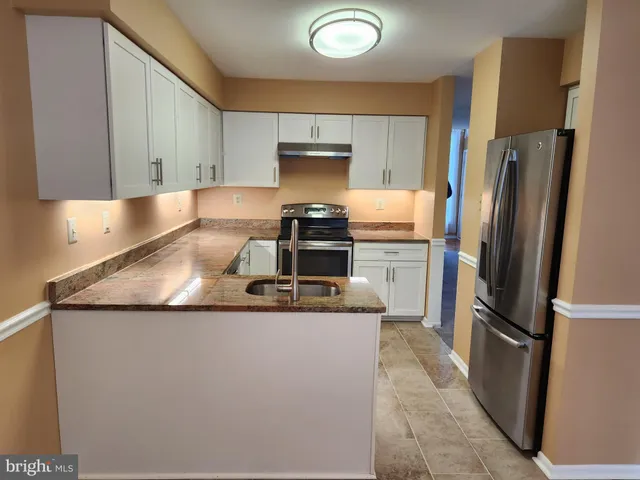 a kitchen with stainless steel appliances granite countertop a refrigerator a stove and a sink