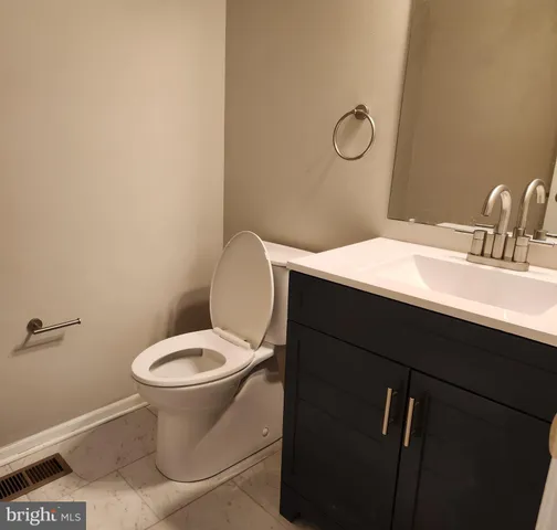 a bathroom with a toilet sink vanity and mirror