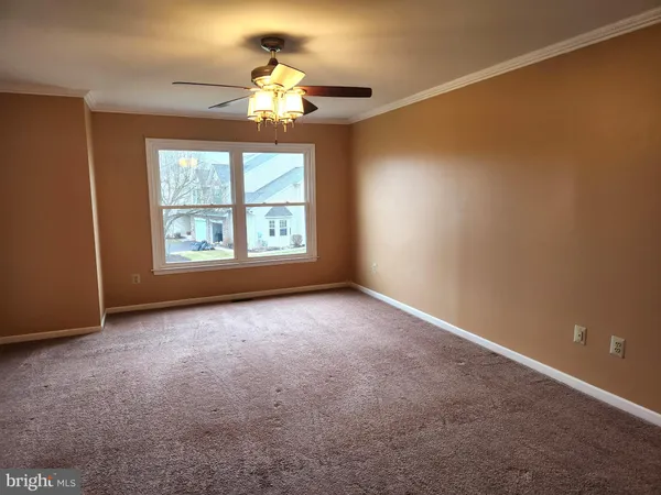 an empty room with a chandelier fan and windows
