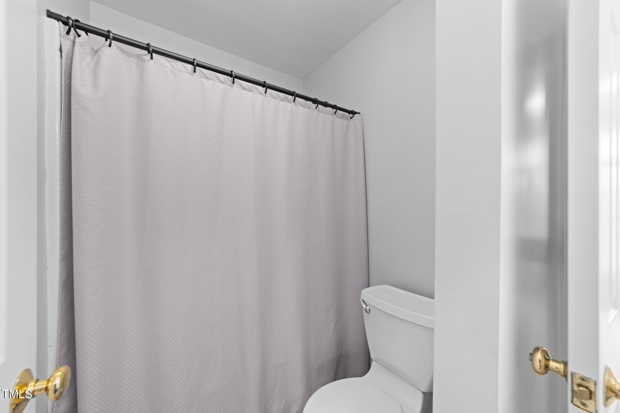 3525 La Costa Way Raleigh, NC 27610 - Photo 28 of 45 a white toilet sitting next to a shower curtain