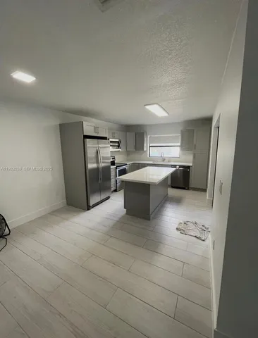 a large white kitchen with a sink and dishwasher a refrigerator with white cabinets