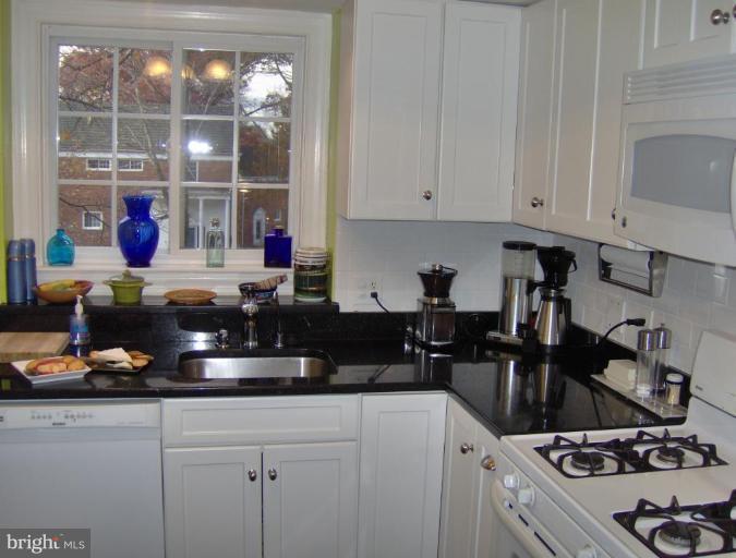 3237 Gunston Road, Unit 104 Alexandria, VA 22302 - Photo 3 of 16 a kitchen with kitchen island granite countertop a sink a stove and white cabinets