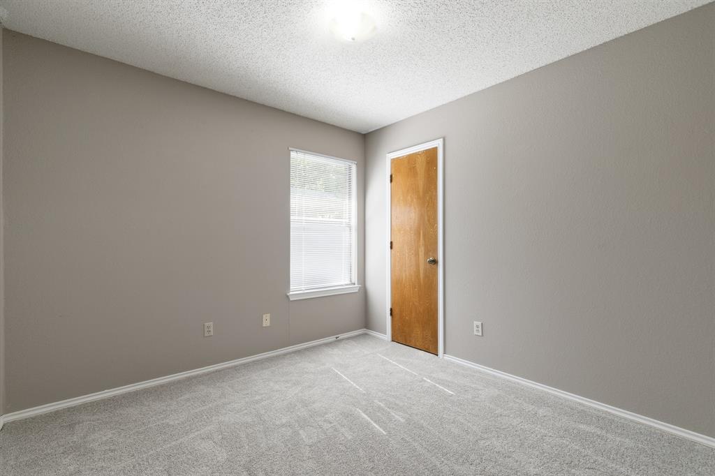 6612 Patsy Lane Watauga, TX 76148 - Photo 22 of 32 Neutral-toned room featuring a single window with blinds, a wood-finish door with white trim, light gray carpet, and white baseboards