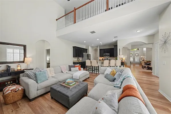 a living room with furniture kitchen view and a wooden floor