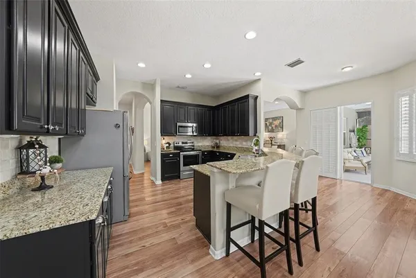a kitchen with stainless steel appliances granite countertop a kitchen island hardwood floor sink and stove