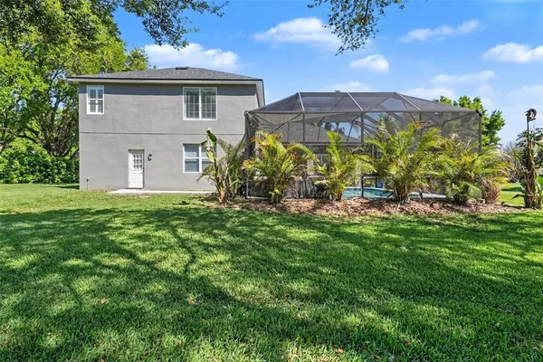 a view of a house with a big yard and large trees