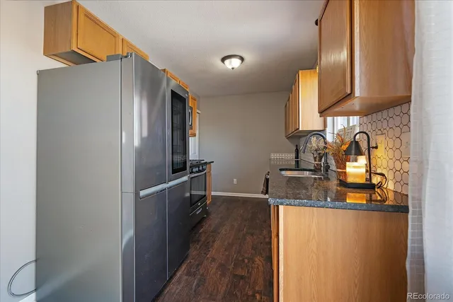 a kitchen with granite countertop a sink stove and refrigerator