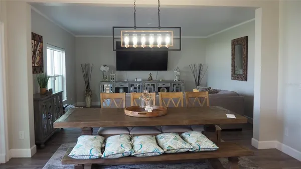 a dining room with wooden floor a chandelier a wooden table and chairs