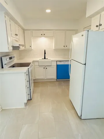 a kitchen with a refrigerator sink and cabinets