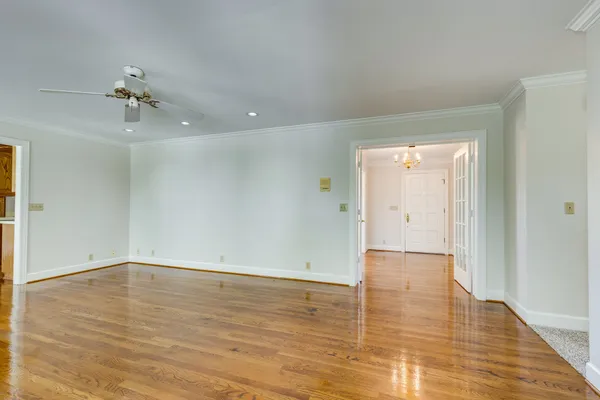 an empty room with chandelier fan and windows