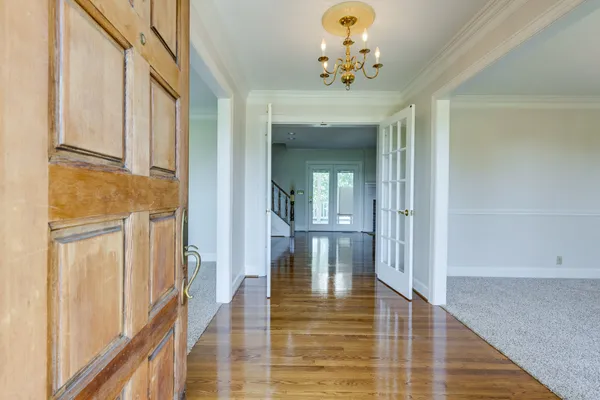 a view of an empty room with wooden floor fireplace and a window