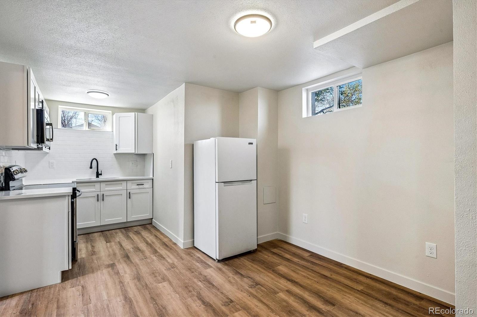 802 Julian Street Denver, CO 80204 - Photo 17 of 17 a kitchen with a refrigerator and white cabinets