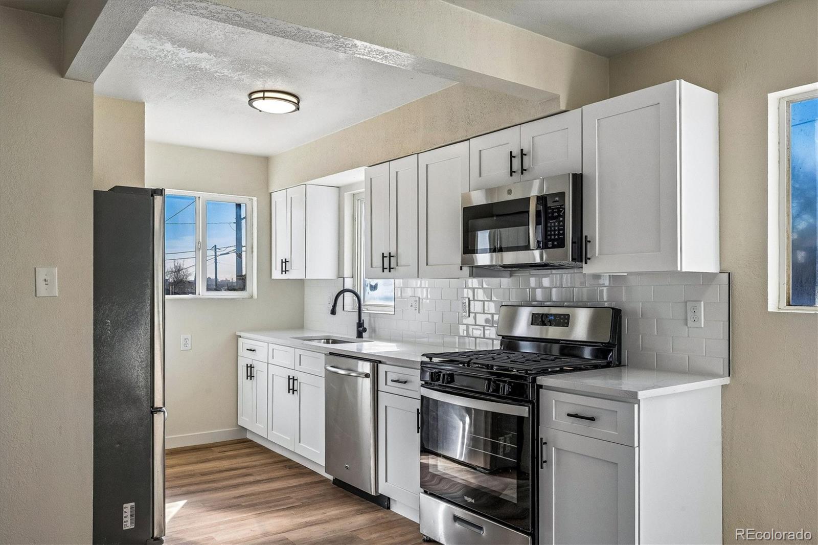802 Julian Street Denver, CO 80204 - Photo 5 of 17 a kitchen with stainless steel appliances a stove a sink and a microwave