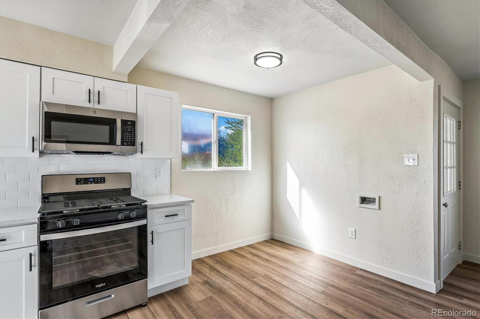802 Julian Street Denver, CO 80204 - Photo 6 of 17 a kitchen with granite countertop a stove top oven a sink dishwasher and microwave with wooden floor