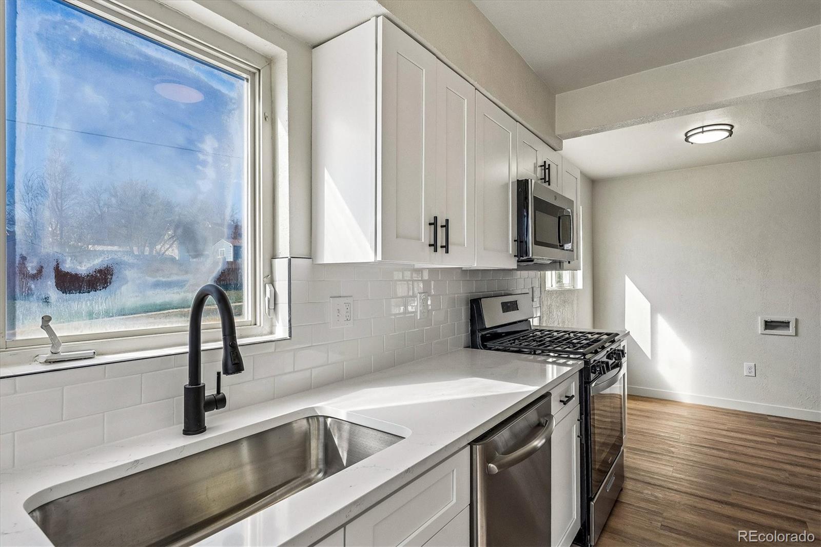 802 Julian Street Denver, CO 80204 - Photo 8 of 17 a kitchen with stainless steel appliances granite countertop a sink and a stove top oven