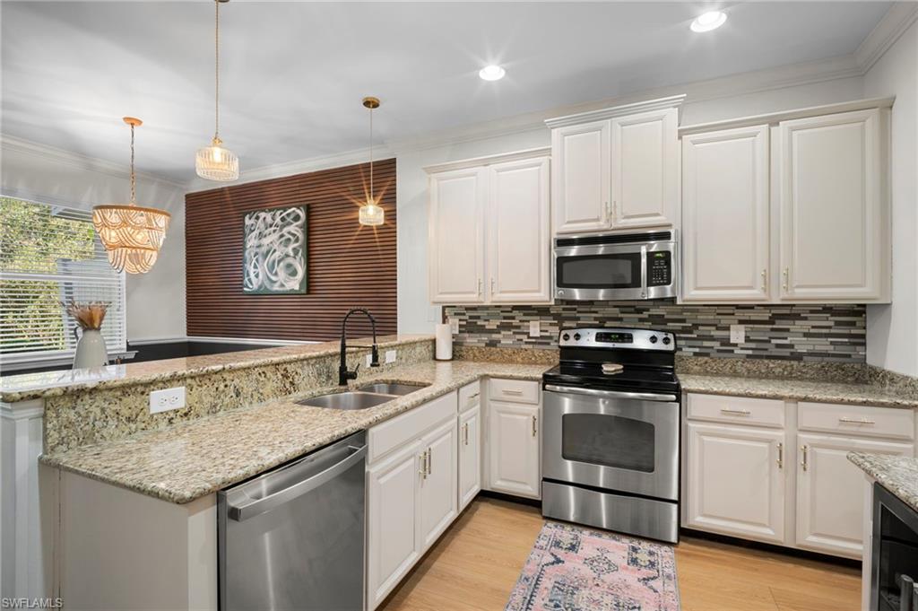 19501 Bowring Park Road, Unit 102 Fort Myers, FL 33967 - Photo 12 of 33 a kitchen with stainless steel appliances granite countertop a sink and dishwasher a stove top oven with white cabinets