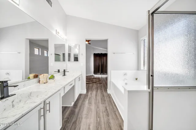 a spacious bathroom with a granite countertop double vanity sink a mirror and a shower