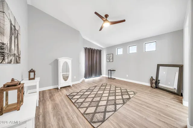 a view of empty room with wooden floor and fan