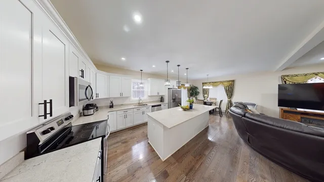 a large living room with stainless steel appliances furniture a flat screen tv and a kitchen view