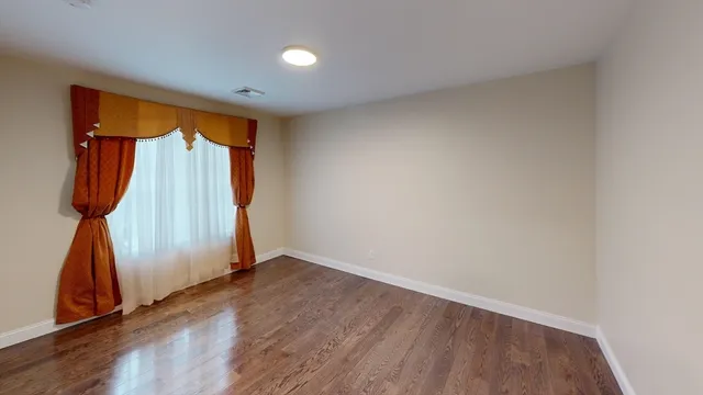 an empty room with wooden floor and a window